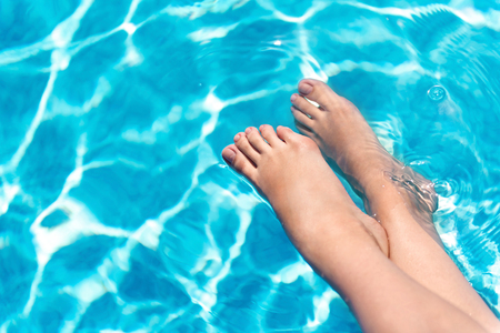 Best relaxation. Close up of legs of a pleasant woman holding them in the swimming poolの写真素材