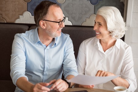 In a good mood. Cheerful delighted smiling colleagues talking and sitting at the table while having lunchの写真素材