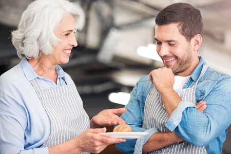 Best receipt. Positive smiling bakers holding croissant and talking while expressing joyの写真素材