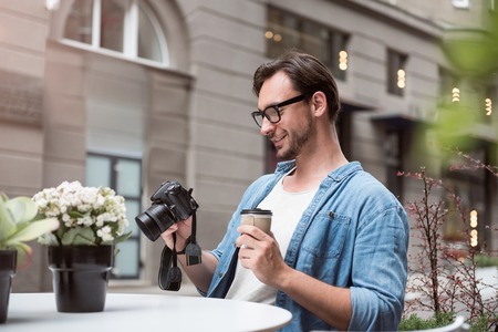 Joyful relaxation. Happy enthusiastic professional photographer looking at the photos and having...