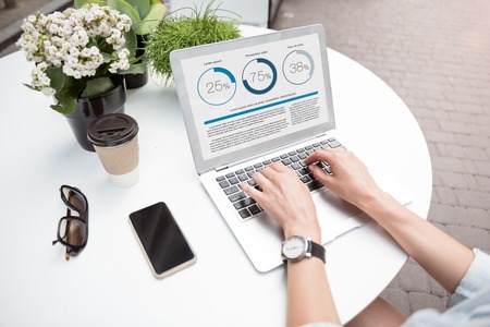 Fulfill the work. Top view of pleasant woman sitting at the table and using laptop while workingの写真素材