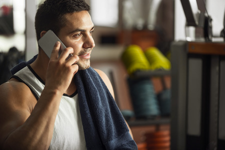 Always in touch. Cheerful optimistic handsome man holding his cell phone and smiling while speaking with somebodyの写真素材