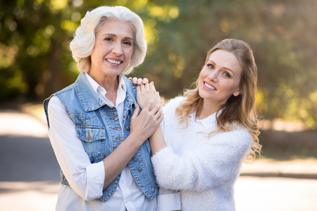 So nice to be your daughter. Delighted happy mom and daughter smiling and embracing while having a walk in the park.の写真素材