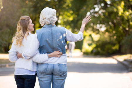 Walk to remember. Relaxed happy mother and daughter hugging and walking while having a rest in the parkの写真素材