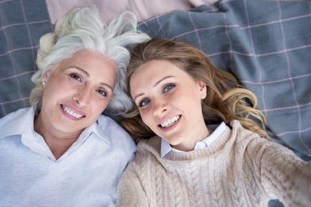 What does it mean to be happy. Two pretty charming women relaxing and smiling while lying on a plaid.の写真素材