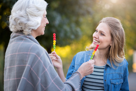 Beautiful life. Two beautiful women smiling and showing each other lollypops while having a walk.
