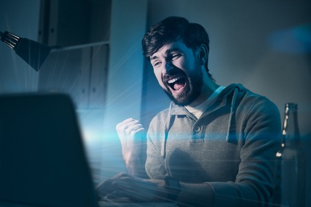 I did it. Handsome young delighted man feeling happy after winning videogame and using a laptop.