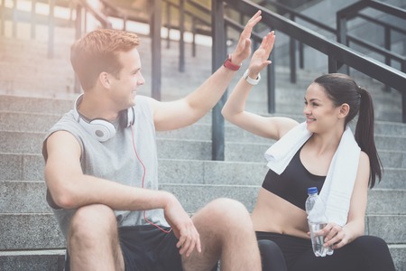 Congrats. Athletic happy young friends giving a high five and smiling to each other before having...
