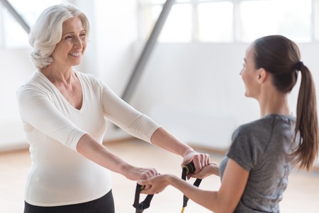 Special equipment for a workout. Persistent energetic positive woman looking at her fitness coach and smiling while exercisingの写真素材
