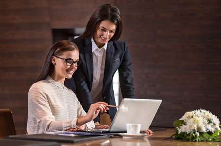 Pretty young female colleagues making project together and working in an office while cooperating.の写真素材