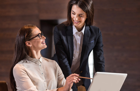 Female young happy colleagues cooperating and working together while sitting in an office.の写真素材