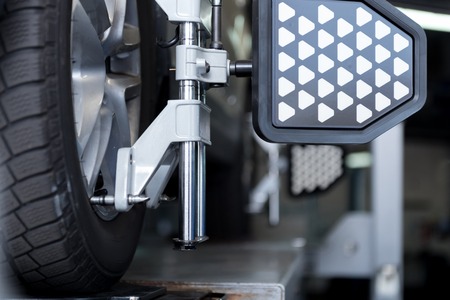 Close up of car tyre clamped in alignment machine device while being checked
