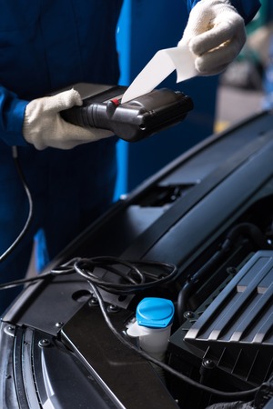Professional mechanic using special device while checking abilities of auto engineの写真素材