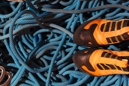 Good equipment. Close up of orange climbing boots standing on blue insurance ropes.の写真素材