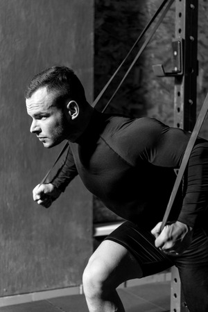 Resistance training exercises. Confident muscular handsome sportsman doing a physical exercise and...