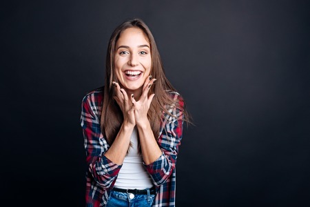 Full of joy. Cheerful delighted young woman smiling and lookign at you while expressing gladnessの写真素材