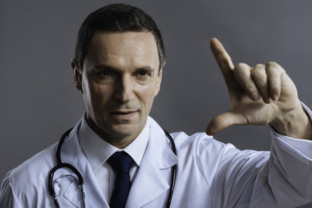 Portrait of concentrated doctor gesturing on a grey backgroundの写真素材