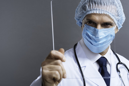 Attractive doctor in face mask holding a glassの写真素材