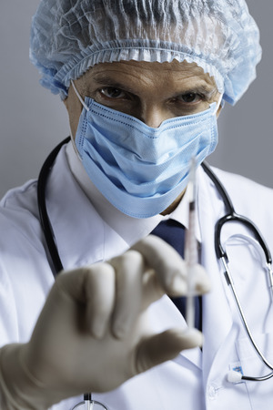 Serious doctor demonstrating hypodermic needleの写真素材