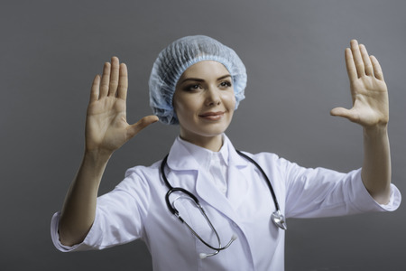 Female doctor putting hands up on grey background.の写真素材