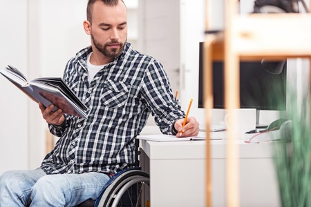 Handsome responsible man writing down quotesの写真素材