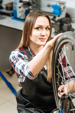 Charming woman repairing the wheel bicycle in the repair shopの写真素材