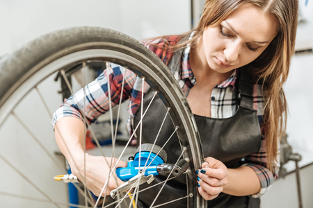 Concentrated craftswoman measuring the pressure of a tireの写真素材