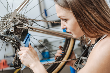 Diligent female technician brushing the chain of the bicycleの写真素材