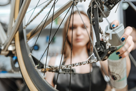 Involved craftswoman fixing the chain of the bicycle