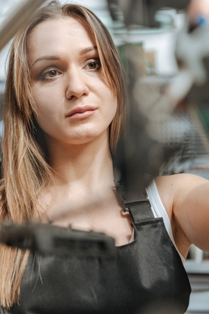 Aware craftswoman fixing the bicycle in the repair shopの写真素材