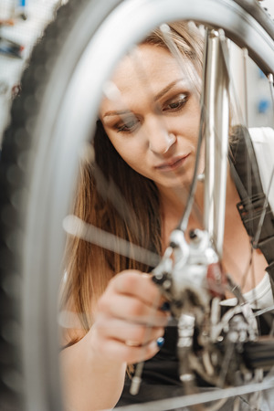 Young mechanic fixing the bicycle in the workshopの写真素材