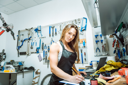Beautiful female technician drawing a draft in the workshopの写真素材