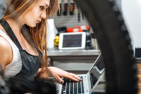 Concentrated female technician using the gadget in the workshopの写真素材