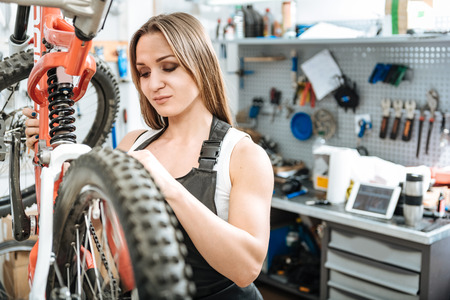 Persevering worker repairing the bicycle in the garageの写真素材