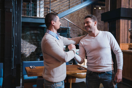 Positive cheerful men greeting each other