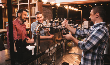 Cheerful bearded bar attender pouring a drinkの写真素材