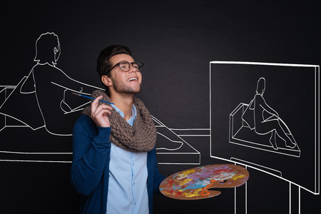 Inspired handsome man holding palette and painting.の写真素材