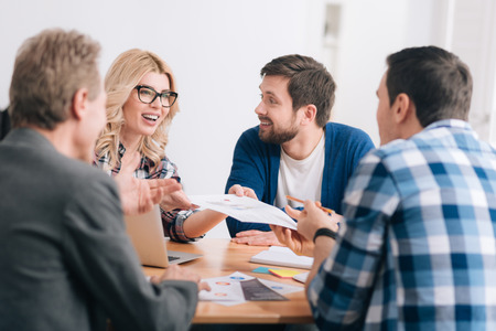 Cheerful attractive woman giving a document to her colleaguesの写真素材
