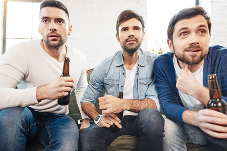 Serious brutal men watching sports games on TVの写真素材