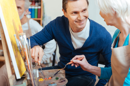 Friendly artist helping elderly woman in paintingの写真素材