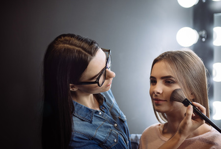 Charming attractive makeup artist using a powder brushの写真素材