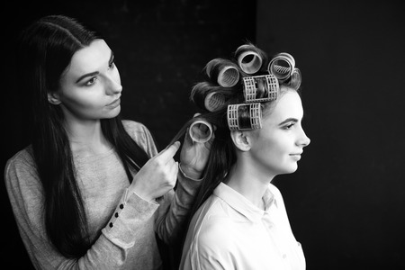 Pleasant cute hairdresser working with hair rollersの写真素材