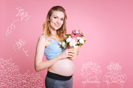 Cheerful pregnant woman holding flower potの写真素材