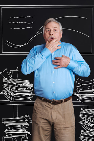 Nice aging man standing among piles of paperの写真素材