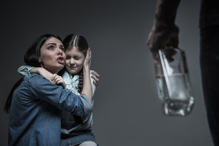 Frightened woman embracing her little daughterの写真素材
