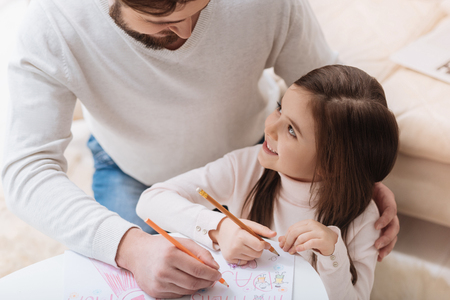 Happy delighted girl sitting with her fatherの写真素材