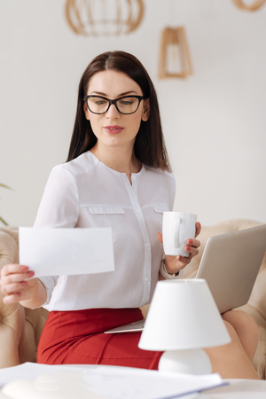 Delighted attractive woman looking at the sheet of paperの写真素材