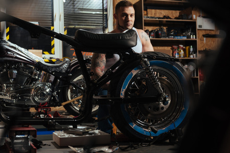 Strong handsome biker being circled with toolsの写真素材