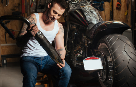 Serious man holding exhaust tube in both handsの写真素材