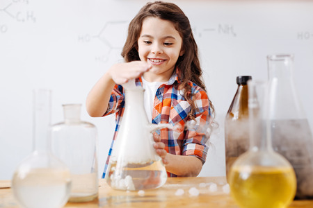 Cute smiling girl holding her hand above the flaskの写真素材